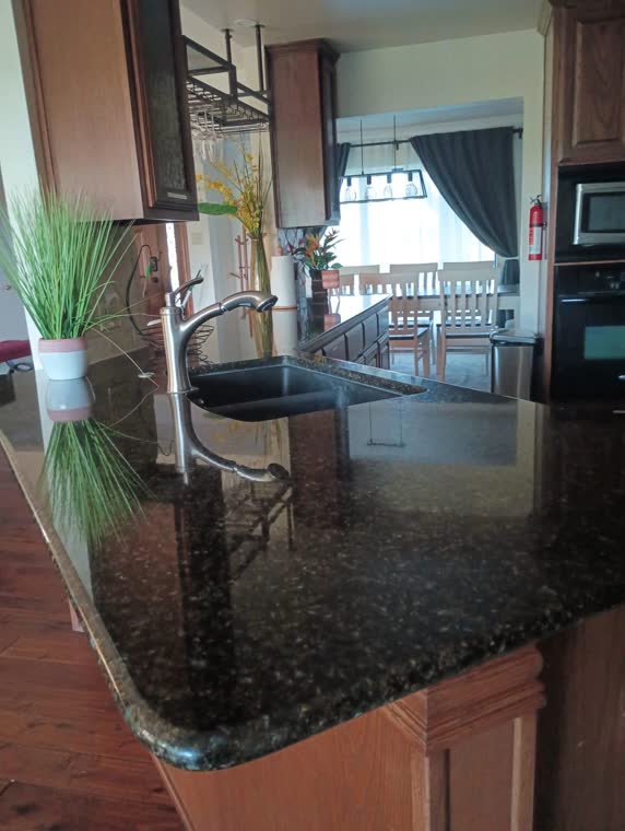 Kitchen with dark granite counters and a sink, opening onto a dining area.