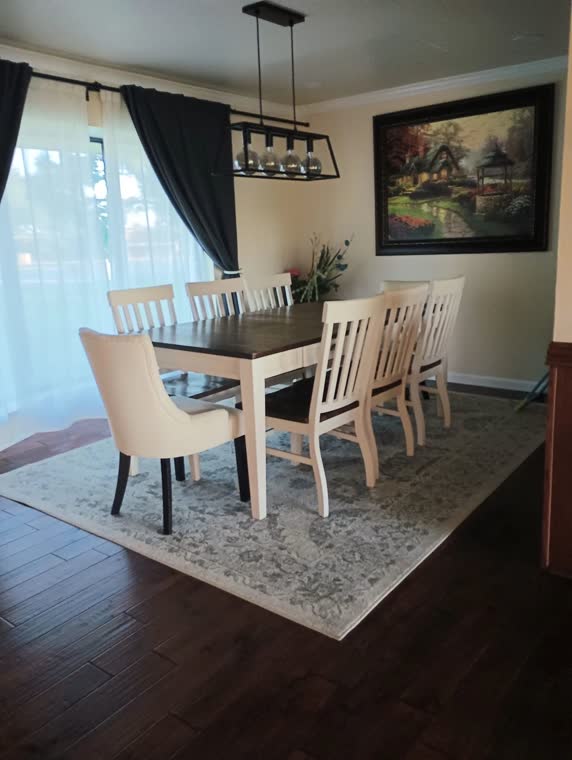 Dining room with a long table, upholstered chairs and a linear chandelier.