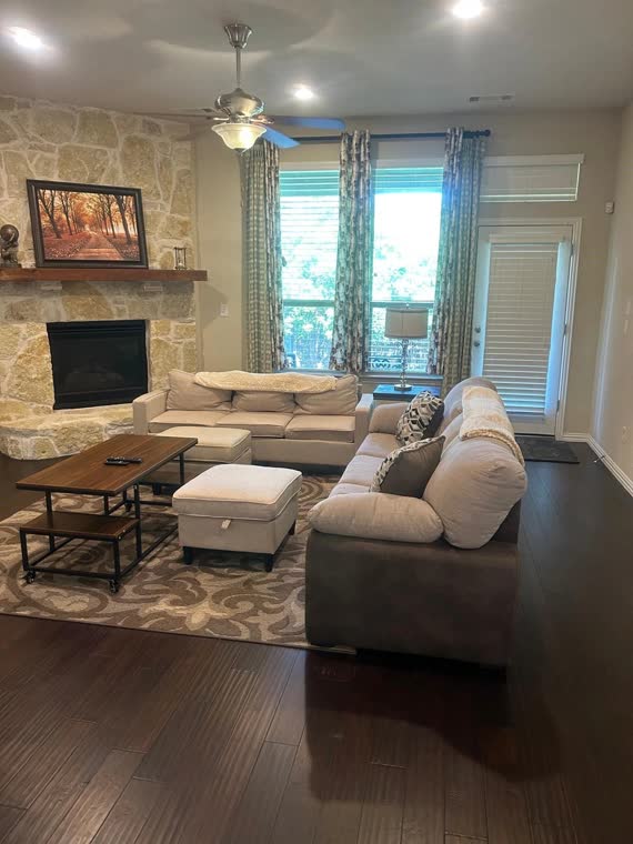 Living room with a stone fireplace and a sectional sofa.